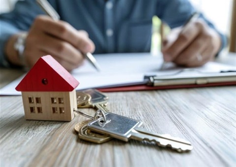 picture of a man signing a mortgage with tiny house and keys in foreground published in from MortgagePoint article.JPG